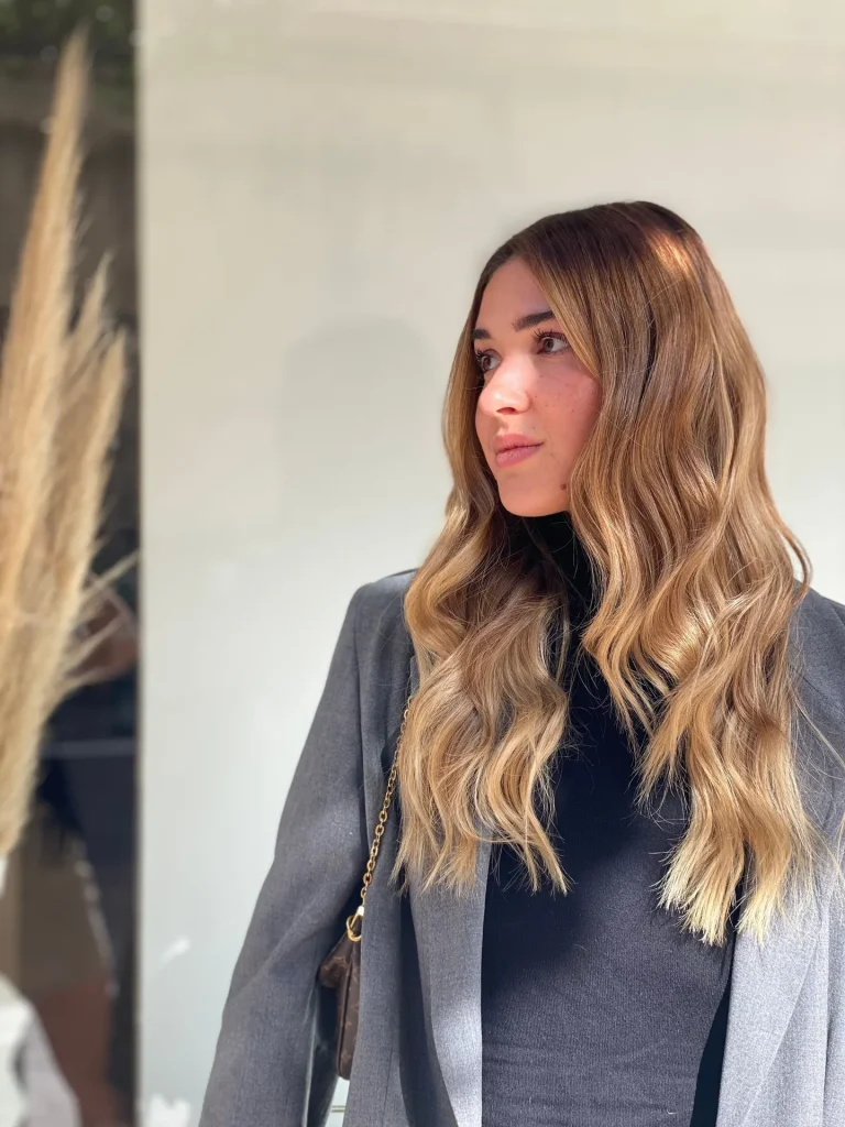 Mulher de cabelo comprido ondulado com casaco cinzento, de perfil