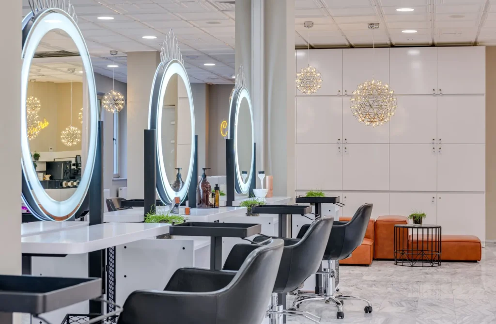 Interior luminoso de um salão com espelhos redondos iluminados e cadeiras cinzentas