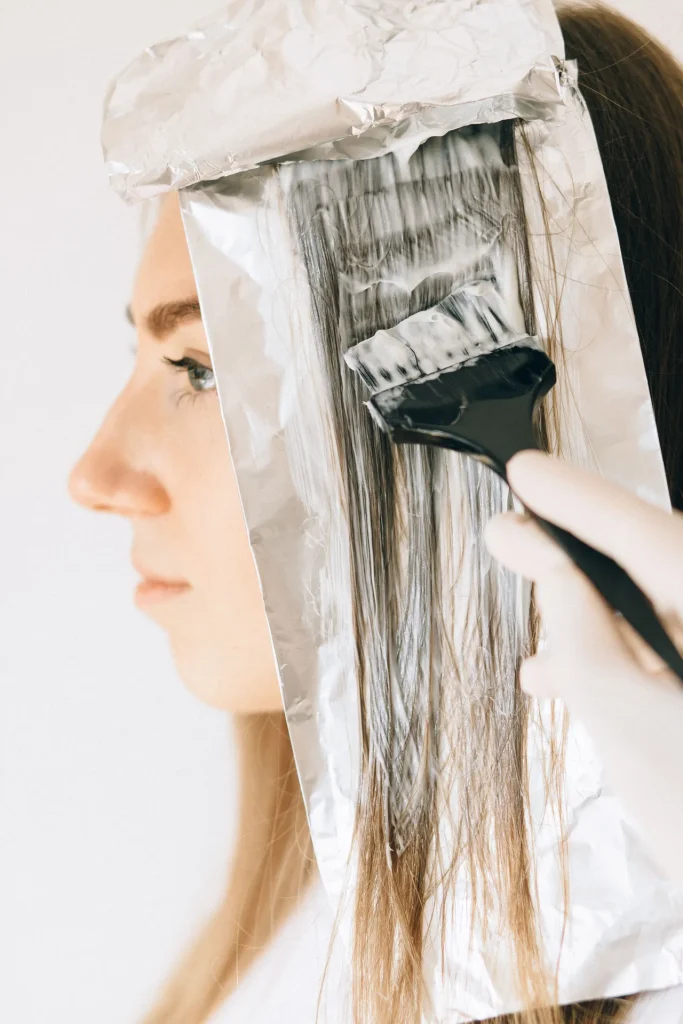 Aplicação de madeixas com pincel e papel de alumínio no cabelo de uma mulher