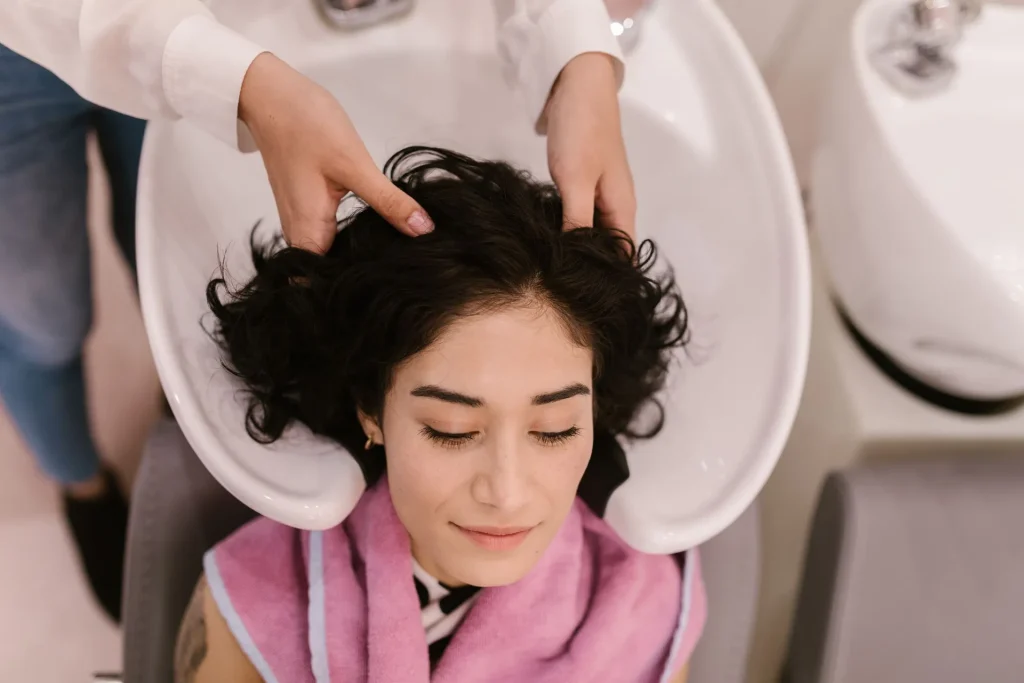Cliente de olhos fechados durante a lavagem e massagem capilar no lavatório do salão